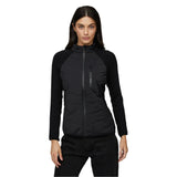 Le Bent Women's Genepi Wool Insulated Hybrid Jacket 2025 - A black jacket with a zippered front and two pockets on either side, featuring a wool insulation pattern on the chest.