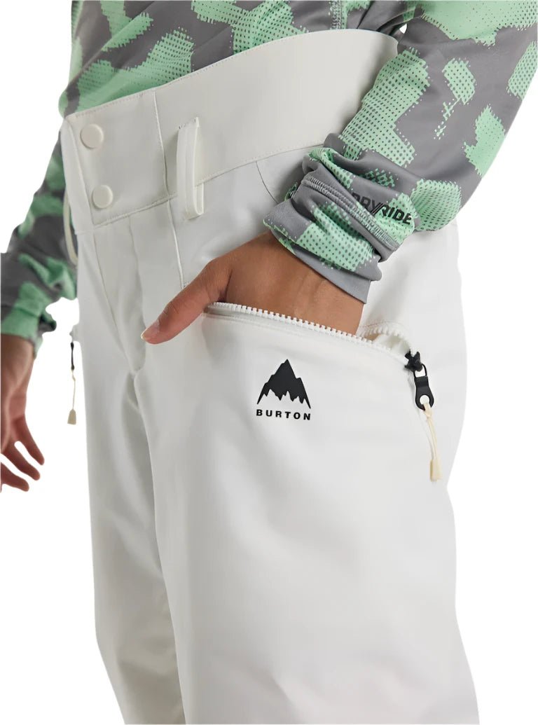 Burton Women's Marcy 2L High Rise Stretch Pants 2025 - A pair of white snow pants with a black logo on the left thigh and a zippered pocket on the right side.