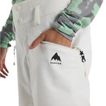 Burton Women's Marcy 2L High Rise Stretch Pants 2025 - A pair of white snow pants with a black logo on the left thigh and a zippered pocket on the right side.