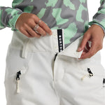 Burton Women's Marcy 2L High Rise Stretch Pants 2025 - A pair of white snow pants with a black stripe down the side and zippered pockets.