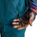 Burton Cargo 2L Shell Pants 2025 - A pair of dark green snow pants with a zippered pocket on the thigh and a black logo patch near the right hip.