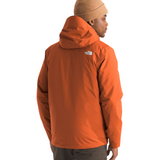 North Face Carto Triclimate Jacket - A man wearing a burnt orange jacket with a white logo on the upper left side of the back, facing away from the camera.