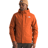 North Face Carto Triclimate Jacket - A man wearing a burnt orange jacket with a white logo on the left chest and two zippered pockets on either side of the waist.