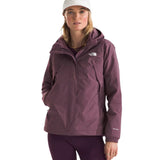 North Face Women's Antora Triclimate Jacket - A woman wearing a purple jacket with a white logo on the left chest, standing against a light gray background.