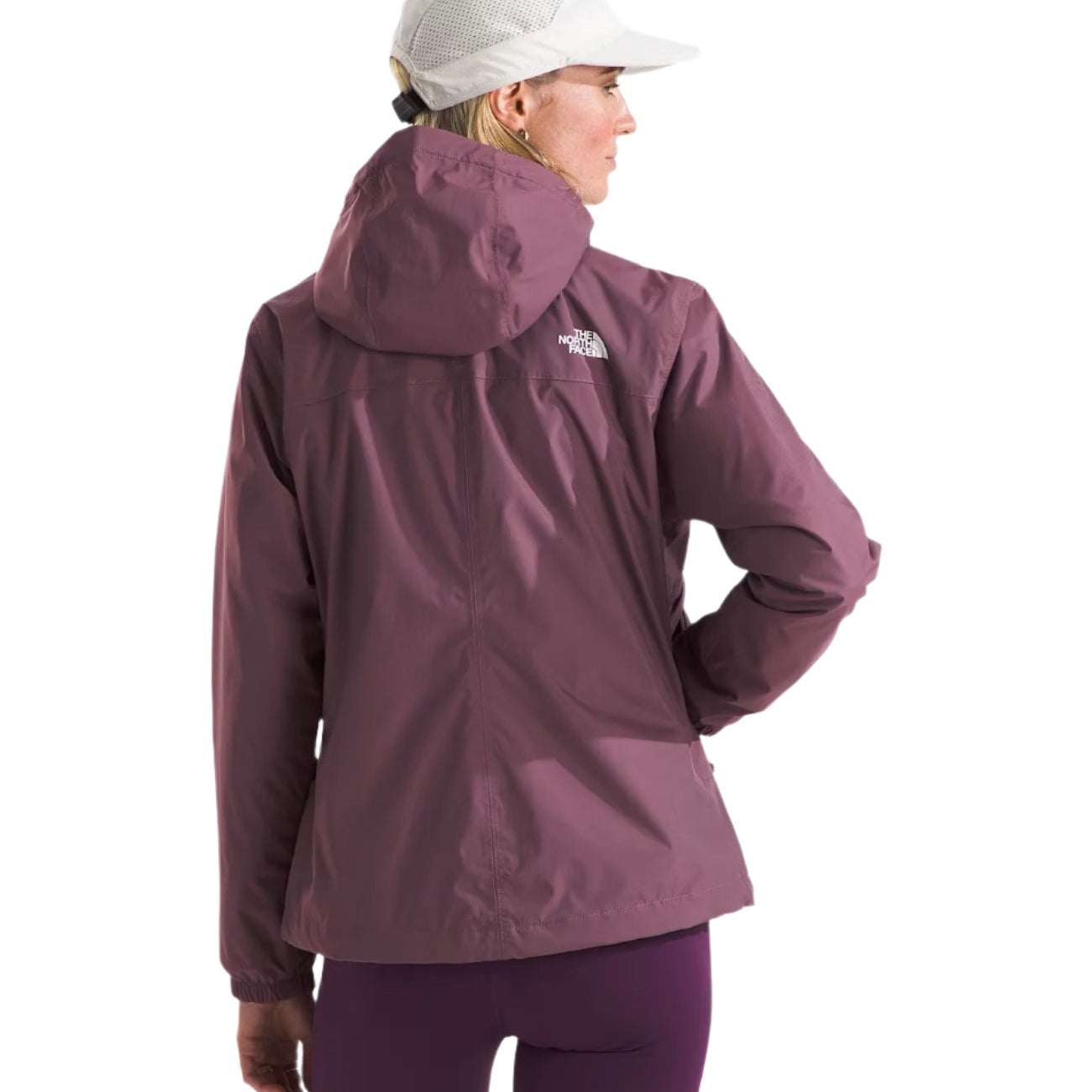 North Face Women's Antora Triclimate Jacket - A woman wearing a white cap and a purple jacket with a hood, standing in front of a light gray background.