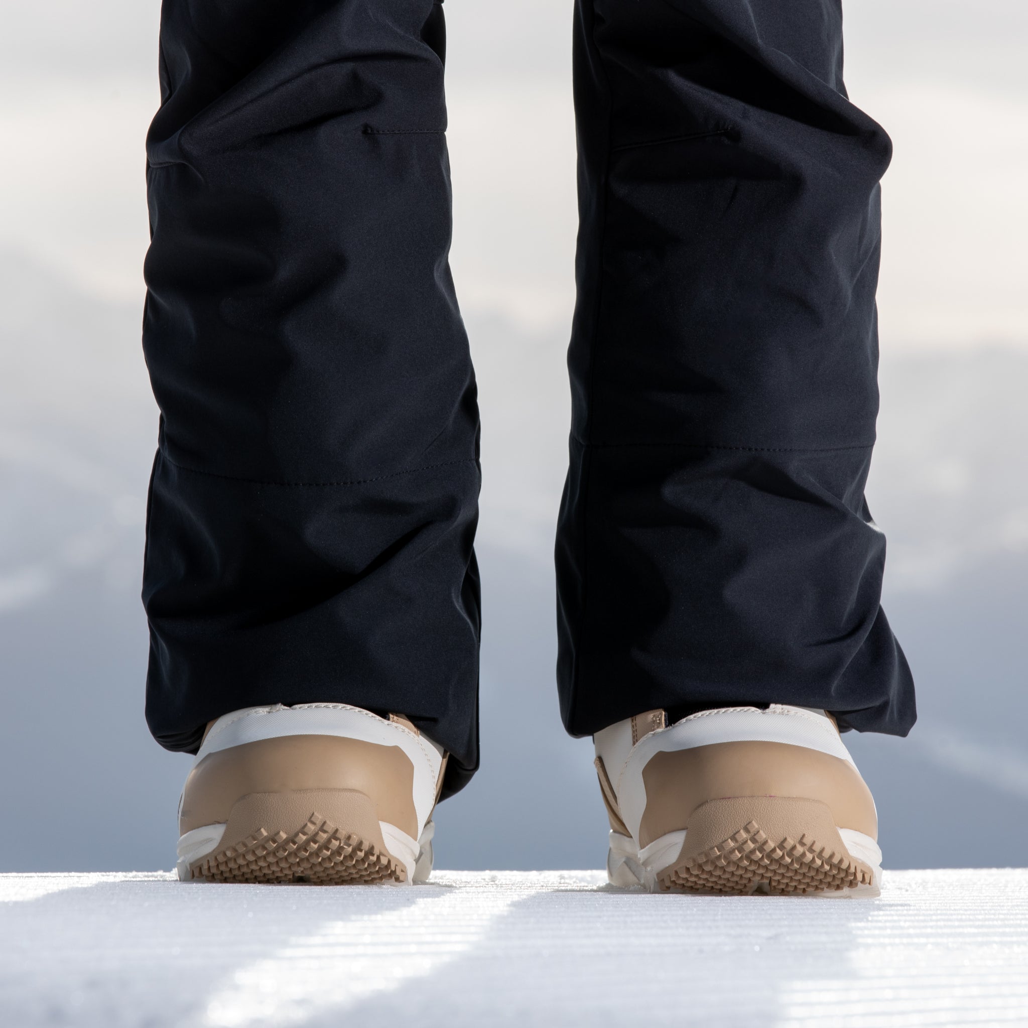 Nidecker Women's Cascade Snowboard Boot 2025 - A pair of black snowboard boots with a tan and white sole, viewed from the back.