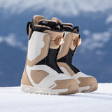 Nidecker Women's Cascade Snowboard Boot 2025 - A pair of tan and white snowboard boots with a black strap on top, featuring a brown buckle.