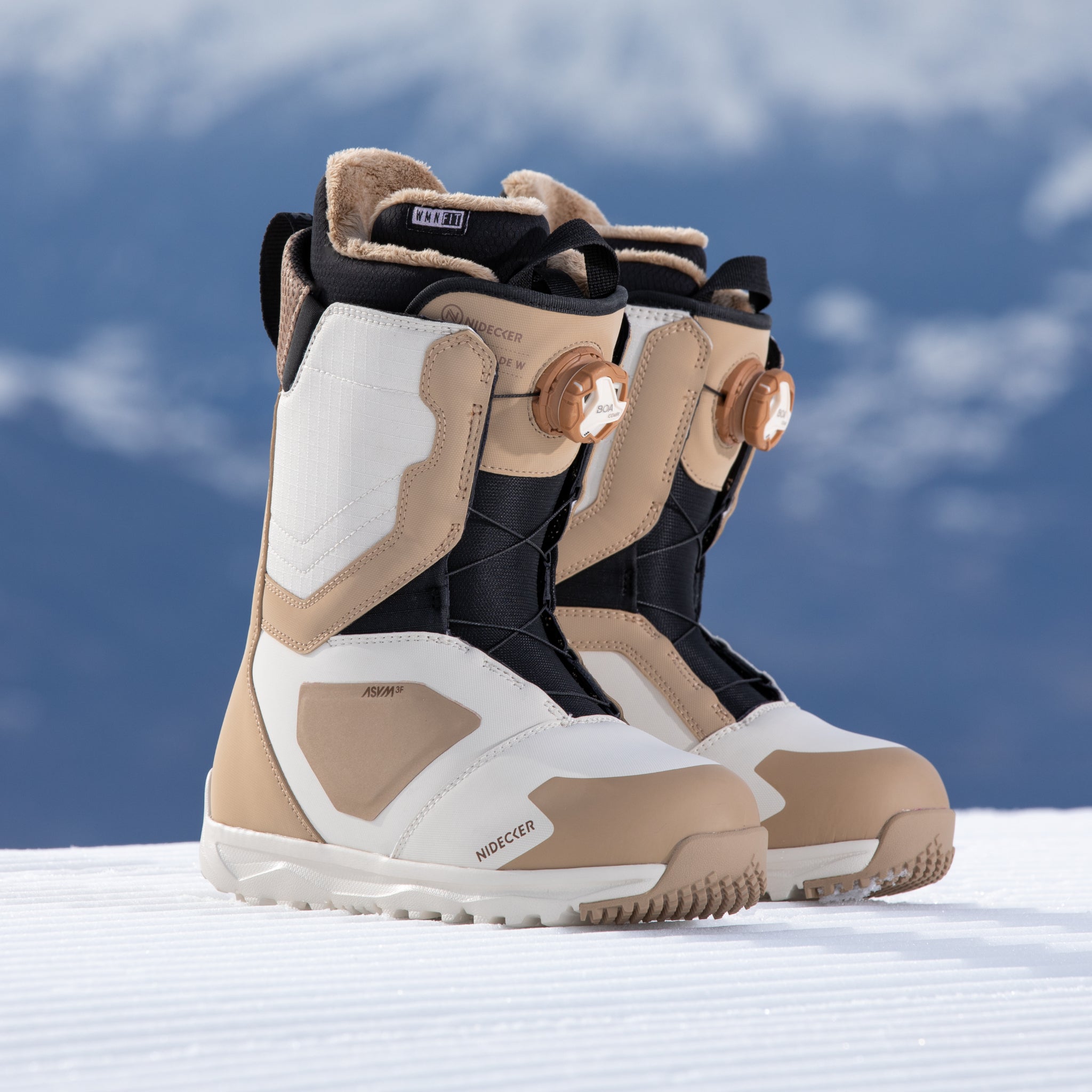 Nidecker Women's Cascade Snowboard Boot 2025 - A pair of tan and white snowboard boots with a black strap on top, featuring a brown buckle.