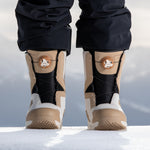 Nidecker Women's Cascade Snowboard Boot 2025 - A tan and black snowboard boot with a white logo on the side, standing in snow.