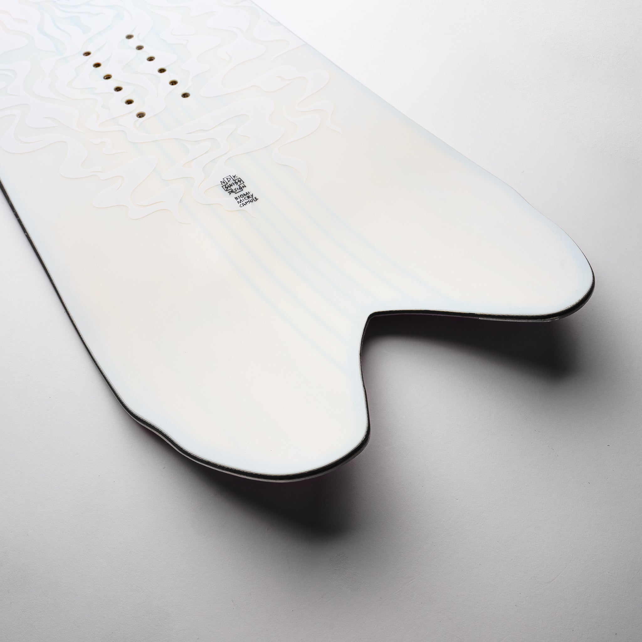Nidecker Beta Snowboard 2025 - A white snowboard with a subtle pattern of light blue lines and dark gray outlines, featuring a black logo on the top left corner.