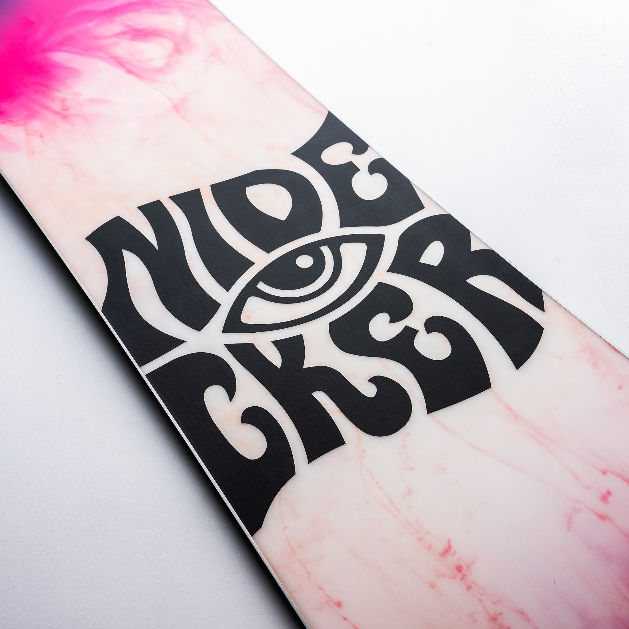 Nidecker Beta Snowboard 2025 - A pink snowboard with a black logo featuring an eye in the center of the word "NIDECKER".