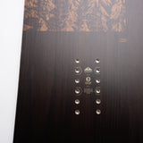 Nidecker Escape Plus Snowboard 2025 - A dark brown snowboard with a wood grain texture and a mountain range design at the top.