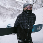 Nidecker Escape Plus Snowboard 2025 - A black snowboard with a white logo on the top sheet, featuring a blue stripe and a small white "Z" in a circle at the tail.