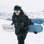 Nidecker Play Snowboard 2025 - A white snowboard with a blue logo and black writing, featuring a dark gray pattern of abstract shapes.