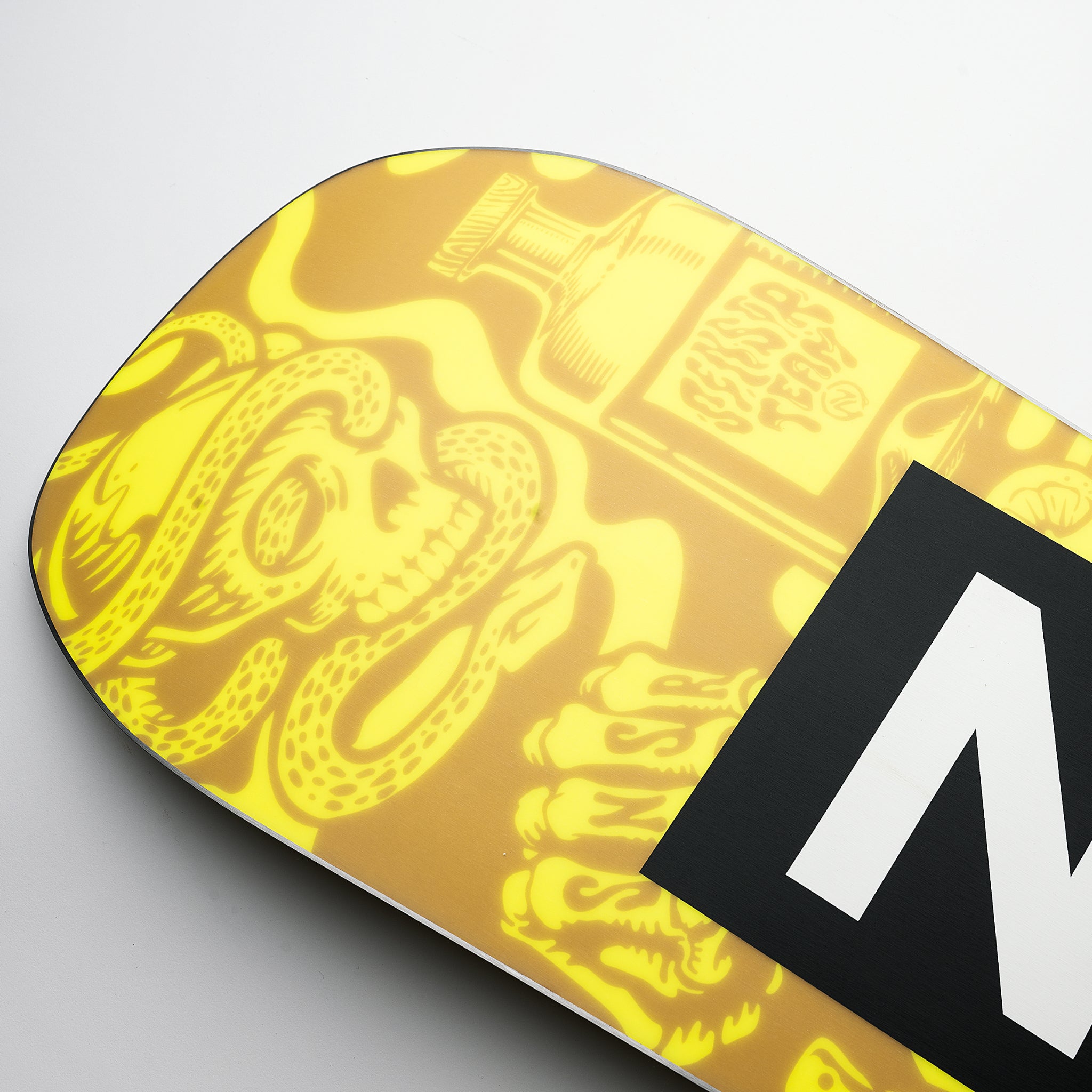 Nidecker Sensor Snowboard 2025 - A yellow snowboard with a repeating pattern of stylized snakes and skulls, featuring a black logo on the top right corner.