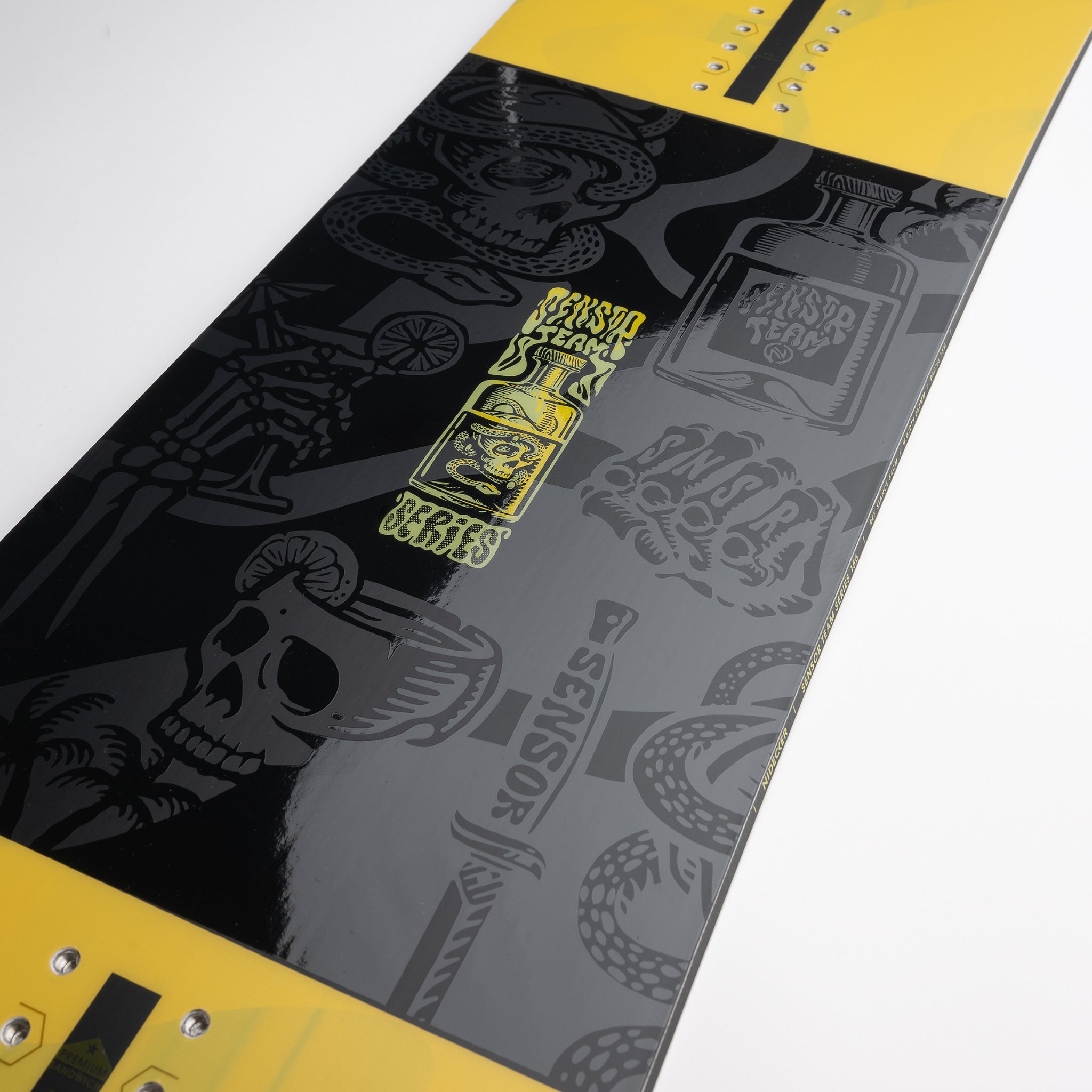 Nidecker Sensor Team Snowboard 2025 - A black snowboard with a yellow logo and graphics of a skull, snake, and palm tree.