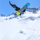 Nidecker Sensor Youth Snowboard 2025 - A blue, green and yellow snowboard with a black logo on top of it is being ridden by a person in mid-air.