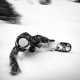 Nidecker The Smoke Snowboard 2025 - A black snowboard with a white and grey abstract design on top of fresh powdery snow.