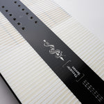 Nidecker Thruster Snowboard 2025 - A black snowboard with a white snake logo and white lettering on top of a light-colored wood grain background.