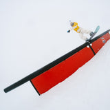 Nidecker Sensor Women's Snowboard 2025 - A snowboard with a black base and white stripes on the top, featuring a rider in a yellow jacket riding it down a snowy slope.