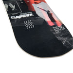 CAPITA - The Outsiders Snowboard 2025 is shown from a top-down perspective, featuring a black background with white and red graphics.