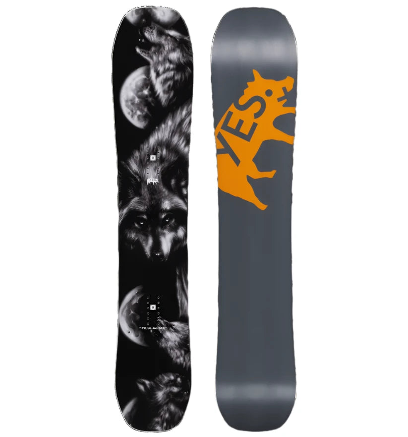 The Yes brand PYL Uninc DCP Xtrm snowboard is black with an orange graphic featuring a wolf silhouette on its front.