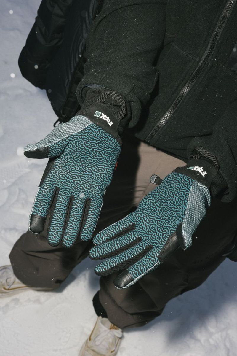 Teal-and-black pipe gloves worn on hands with black jacket sleeves