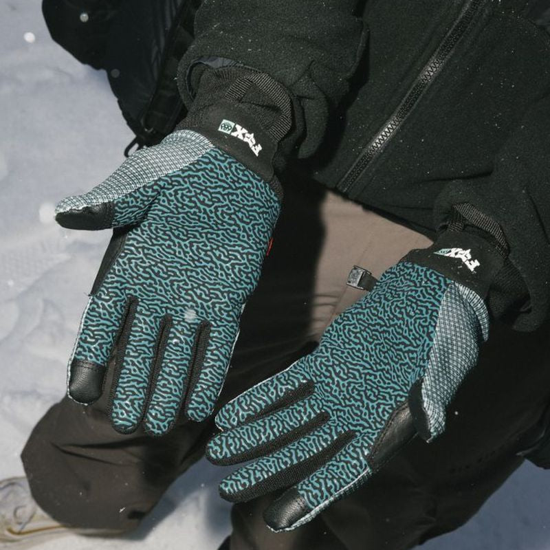 Teal-and-black pipe gloves worn on hands with black jacket sleeves