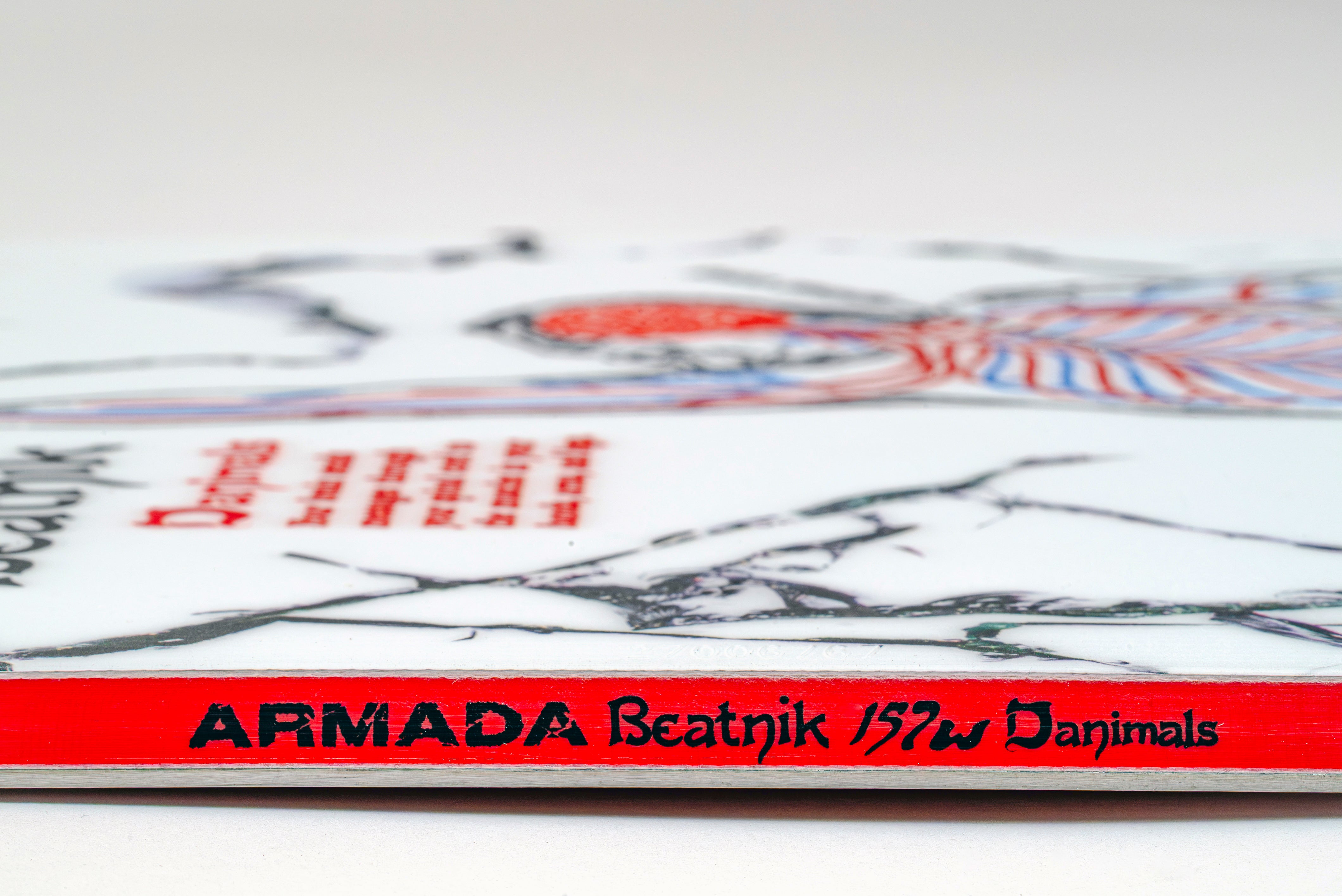White snowboard with “ARMADA Beatnik” logo on the red edge stripe.