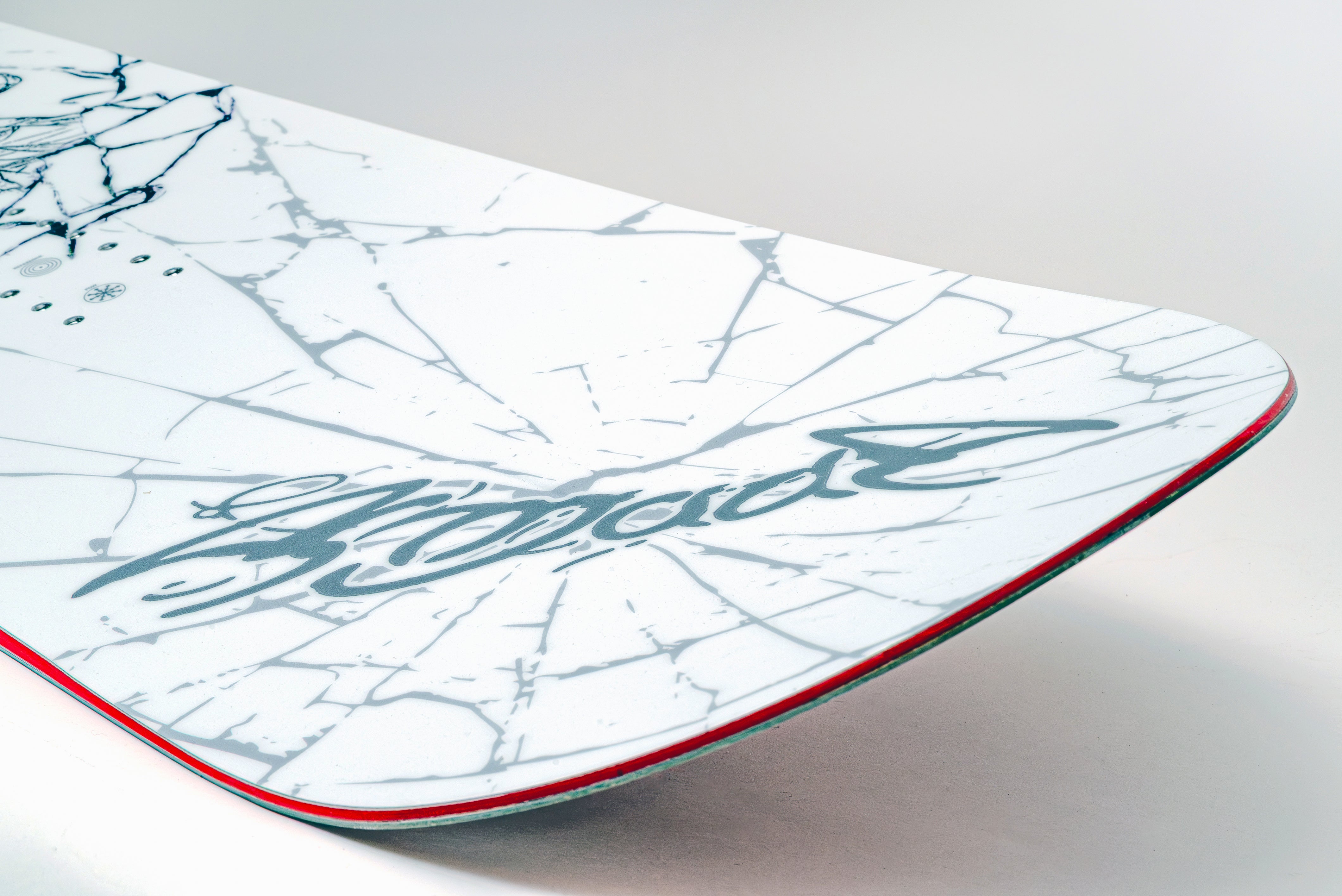 White snowboard with blue signature-style graphic and red sidewall line.