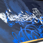 Close-up of dark blue snowboard with white script graphics and blue artwork