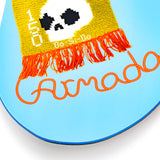 Light blue snowboard tip with yellow patch, black dots, and orange fringe