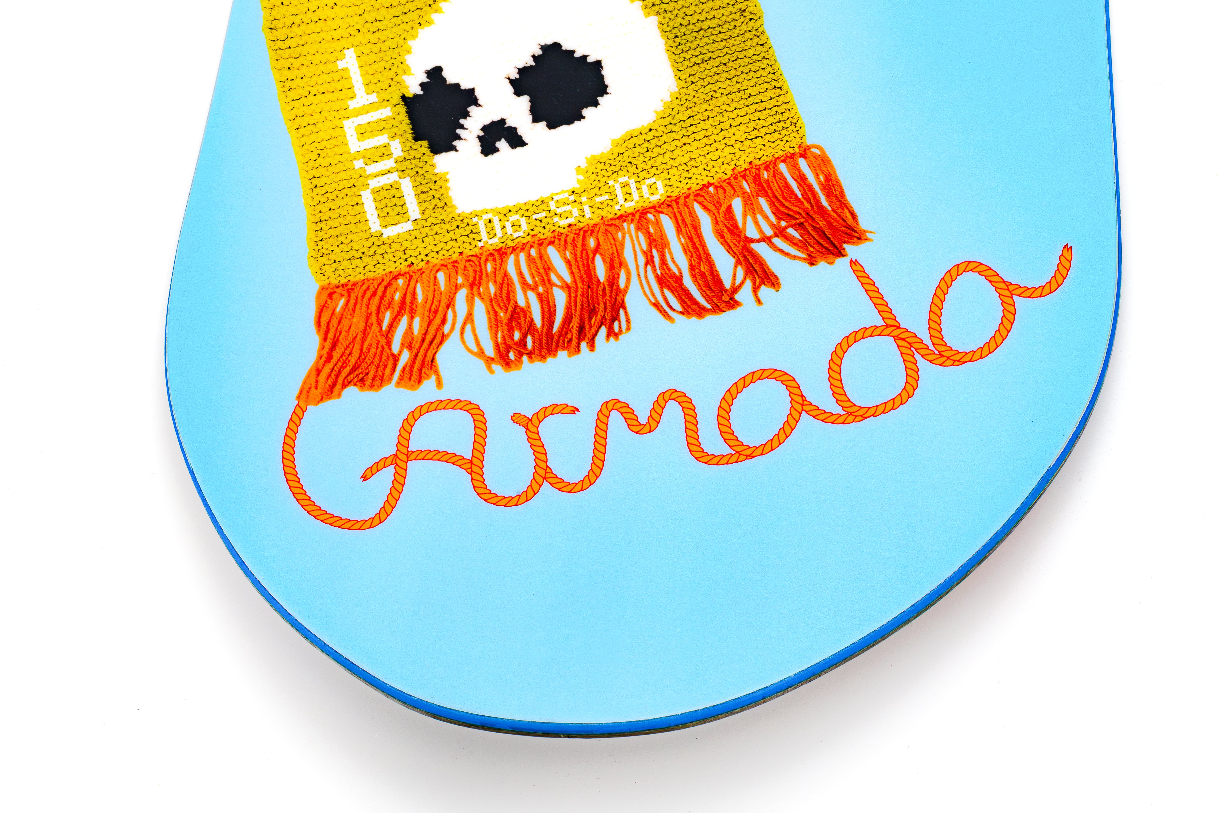 Light blue snowboard tip with yellow patch, black dots, and orange fringe