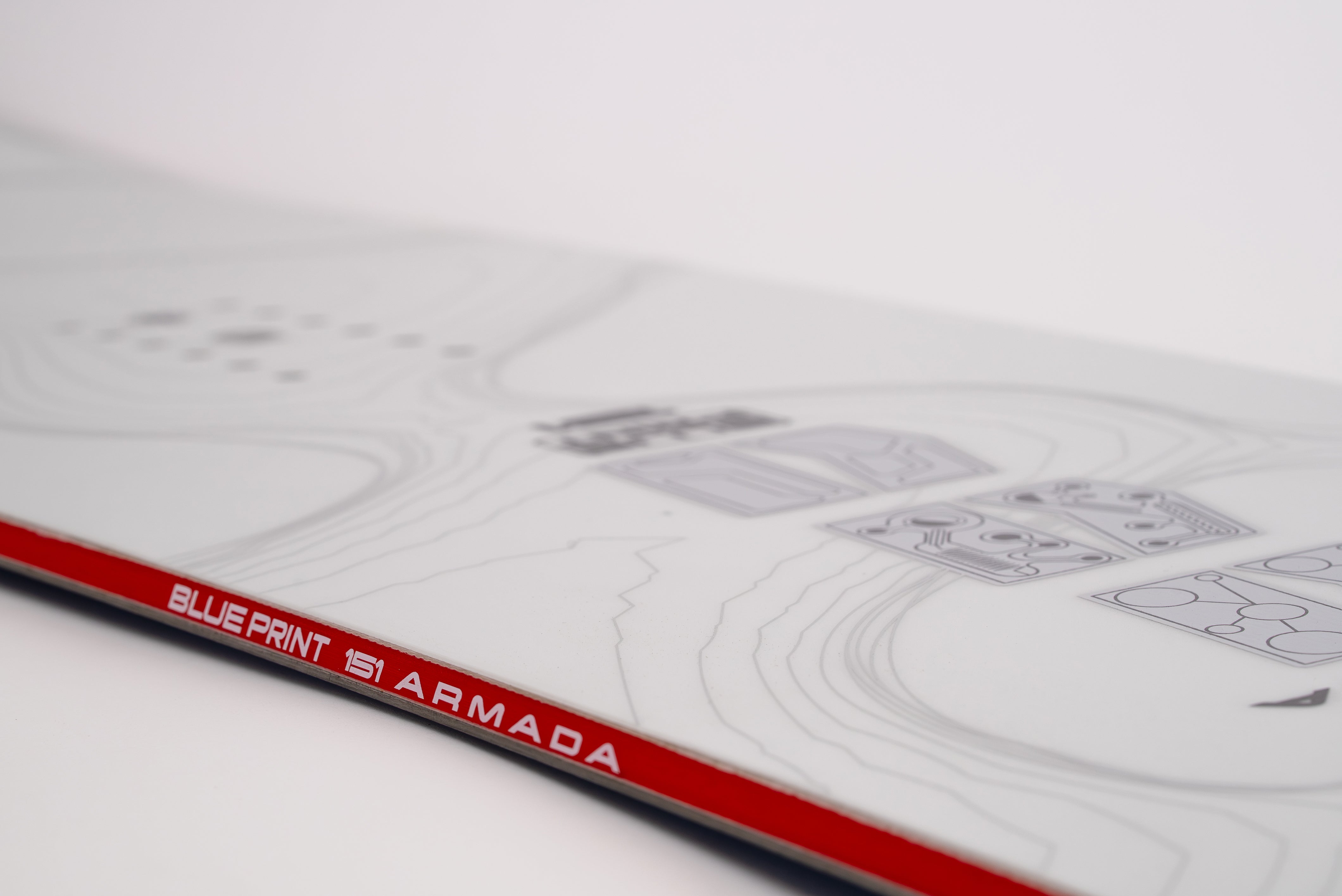 White snowboard close-up with Blueprint 1|1 Armada text and red/black rail