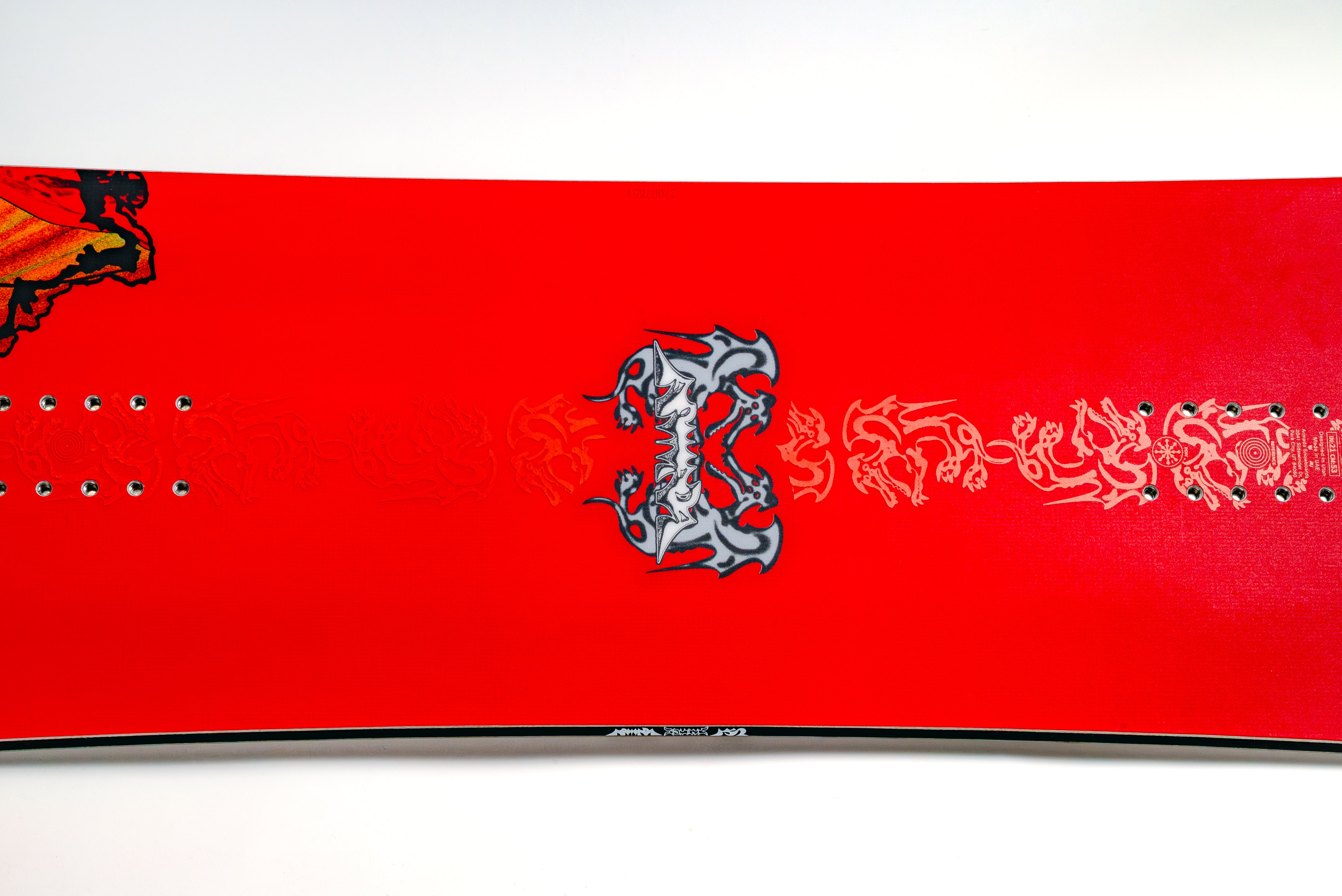 Red snowboard deck with central logo and decorative graphics