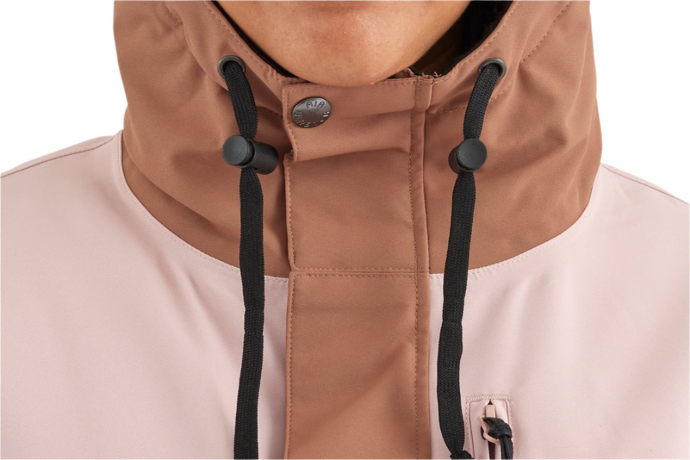 Airblaster Women's Stay Wild Insulated Jacket 2025 - A woman wearing a light pink jacket with a high collar and black drawstrings.