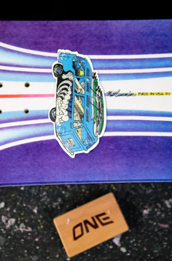 Oneball MC Bus Stomp Pad 2025 - A blue bus with a white roof and black wheels, facing left on a purple background.