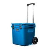 Yeti Roadie 48 Wheeled Cooler - A blue wheeled cooler with a handle on top and two wheels at the bottom.