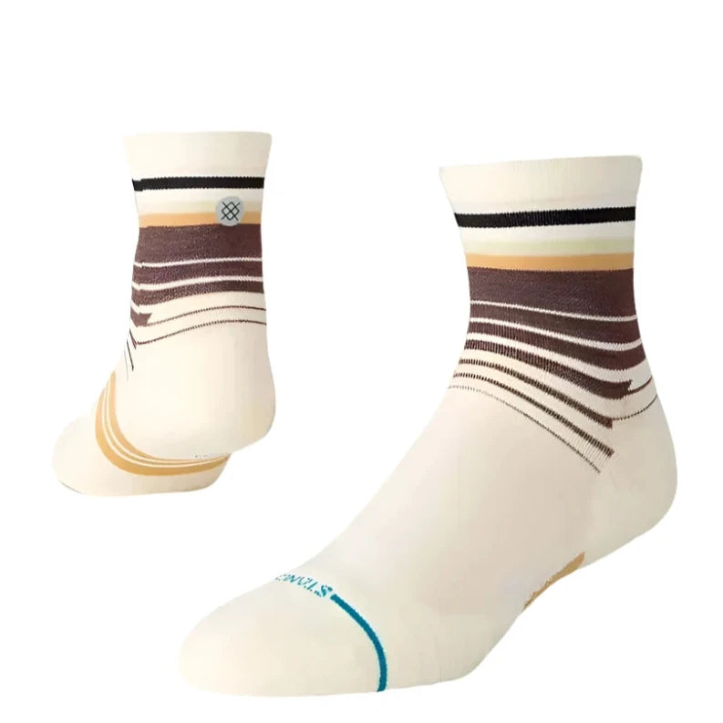 TRACKING QUARTER C SOCK 2025 - A pair of white socks with brown stripes and a blue stripe at the toe.