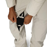 Close-up of off-white insulated bib overalls with black inner gaiter and side zipper opening.