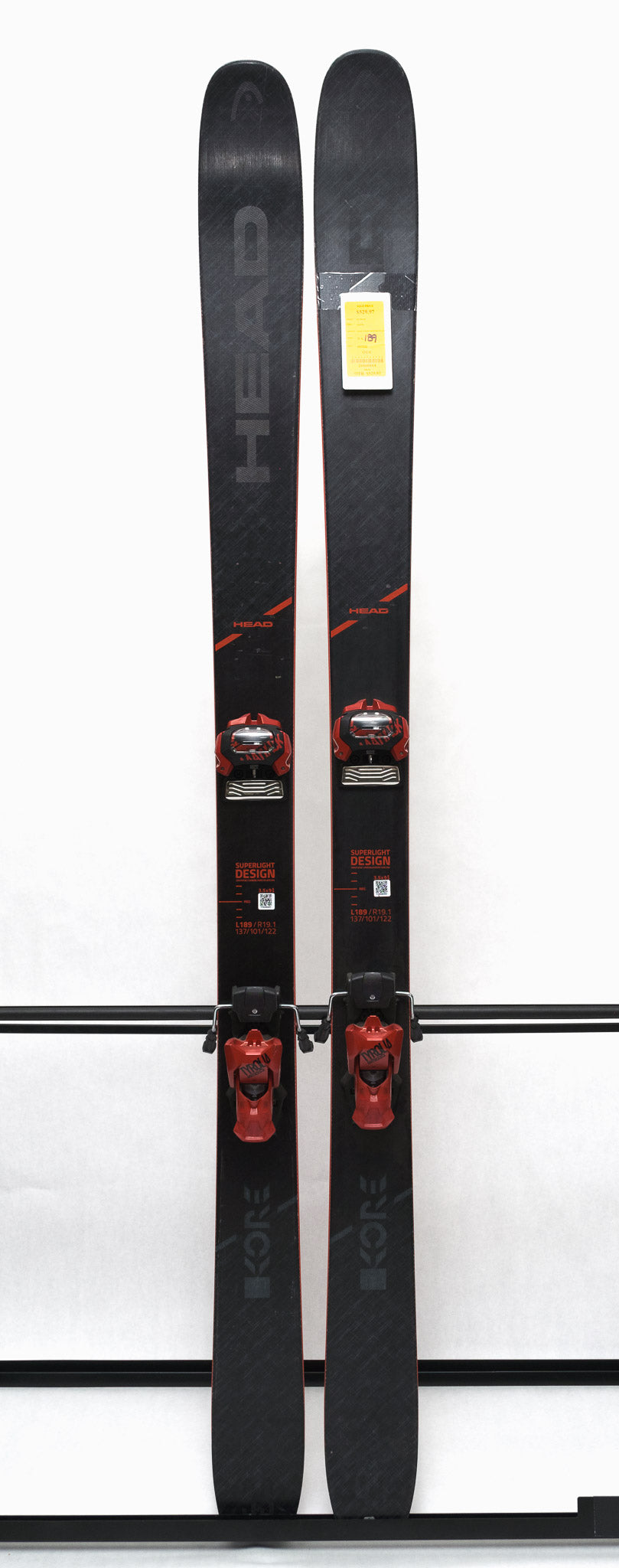 USED - Head Kore 99 with Attack 14 Bindings - A pair of black skis with red bindings and a white tag on the left ski.
