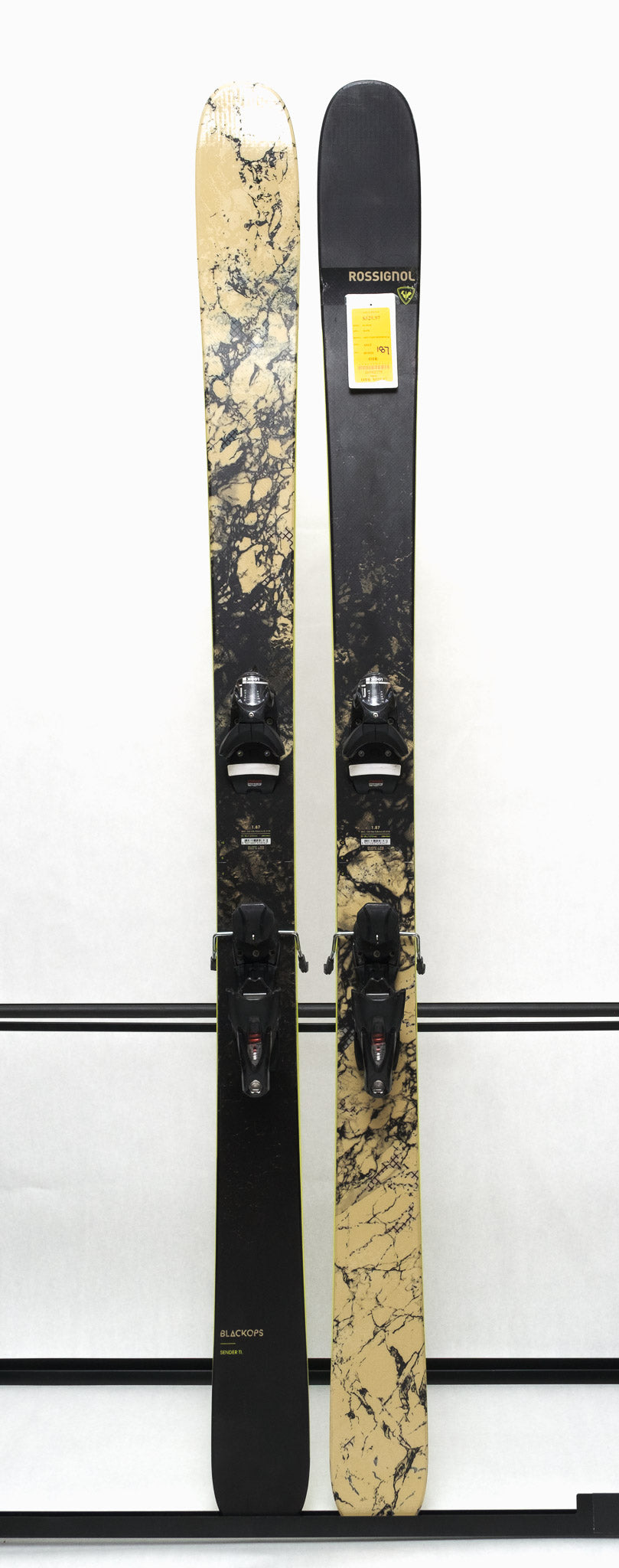 USED - Rossignol Black Ops Sender Ti with SPX 12 Bindings - A black ski with a marbled yellow and black pattern on the tip and tail, featuring silver bindings.