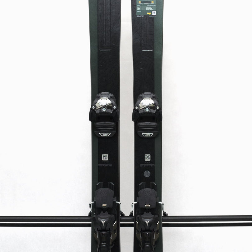 USED - Salomon Stance 90 2022 with Warden 13 Bindings - A pair of skis with a dark green base color and white lettering, featuring the Salomon logo on the top.