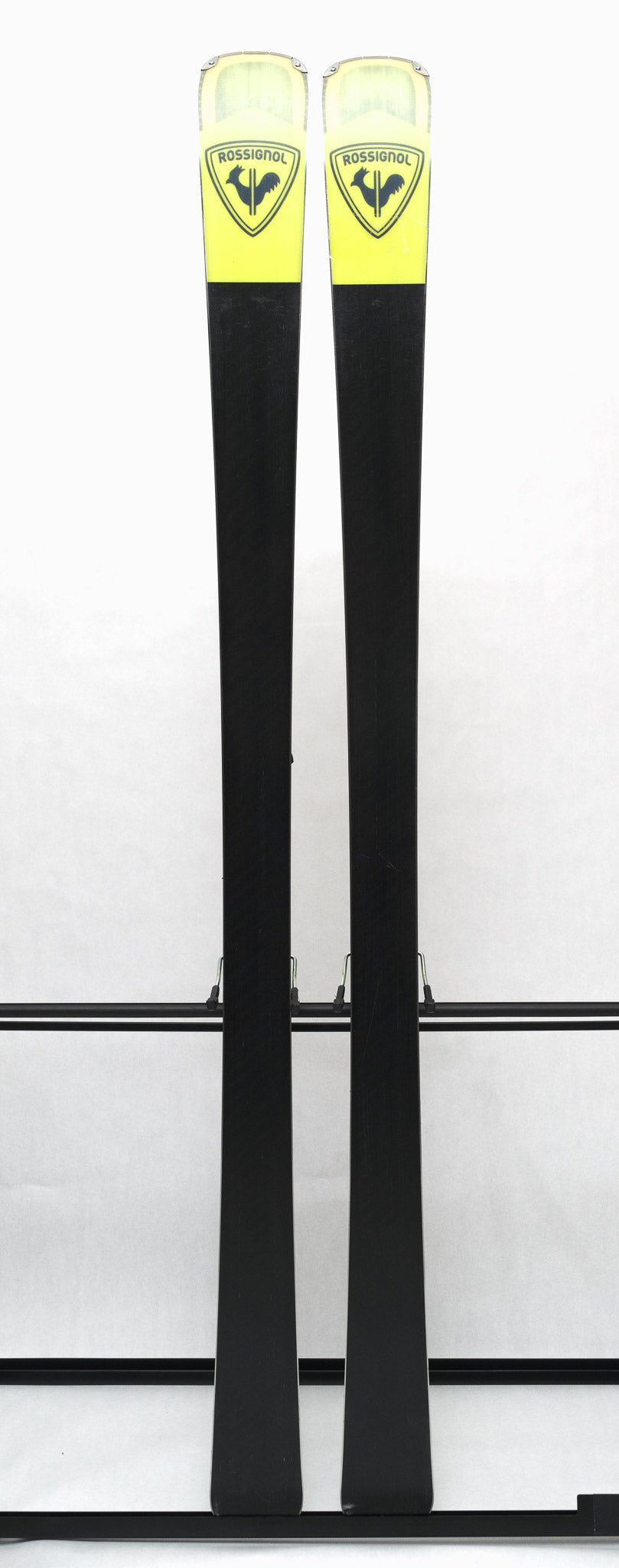 USED - Rossignol Arcade 84 with SPX 12 Demo Bindings - A pair of skis featuring a yellow and black color scheme, with a distinctive rooster logo on the top of each ski.