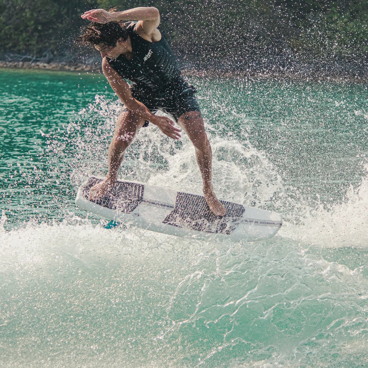 Kanuk Burnsy Pro Wakesurf 2024 - A white wakesurfer with a black logo on the side, floating on calm water.