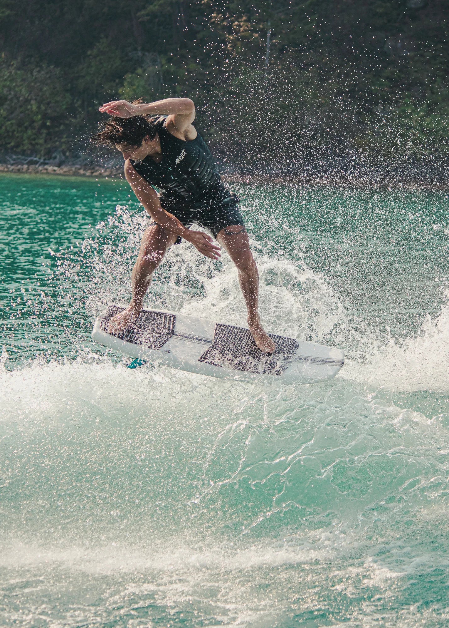 Kanuk Burnsy Pro Wakesurf 2024 - A white wakesurfer with a black logo on the side, floating on calm water.