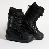 Black lace-up snowboard boots with side ankle straps and thick lugged outsole.