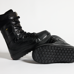 Black snowboard boot low-angle view showing lace-up top and textured tread outsole.