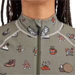 Airblaster Women's Hoodless Ninja Suit 2025 - A sage green onesie with a repeating pattern of cartoon-style illustrations, including skiers, snowboarders, and various winter-themed icons.