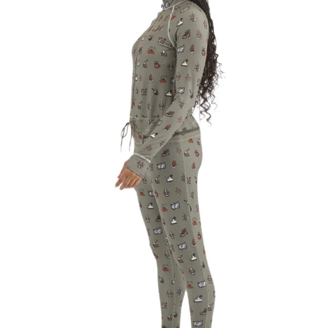 Airblaster Women's Hoodless Ninja Suit 2025 - A woman with long dark braids wears a sage green ninja suit adorned with small, repeating images of various snowboard boots and bindings in red, white, black, and brown.